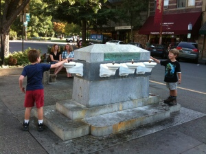 The boys amuse local teens as they splash each other at a fountain in downtown Ashland